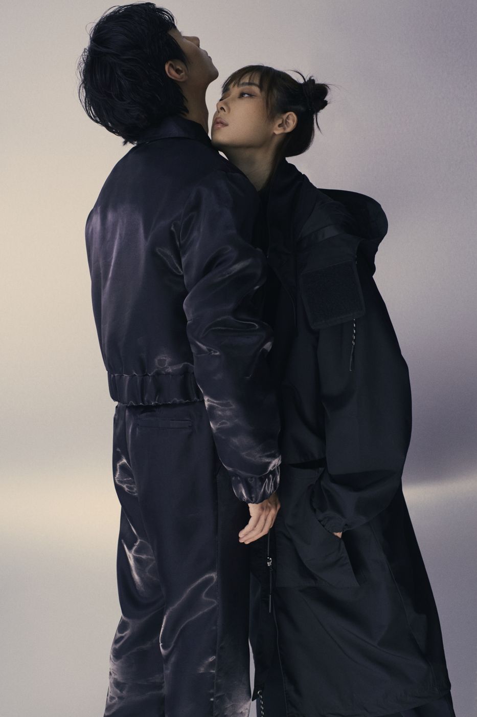 Two people leaning into each other, glossy black coats