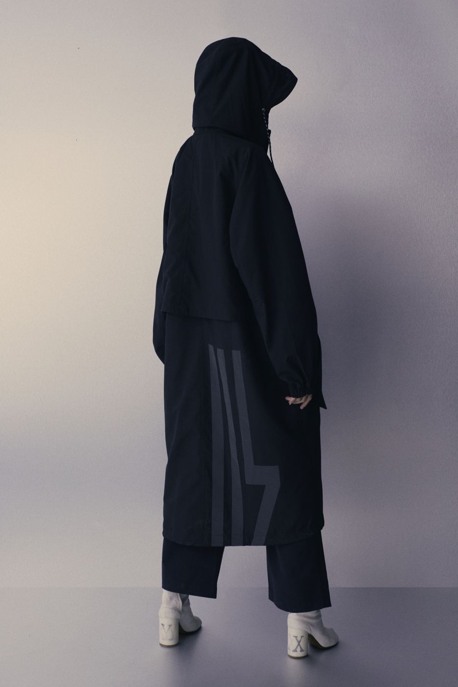 Long black coat, standing with the back turned