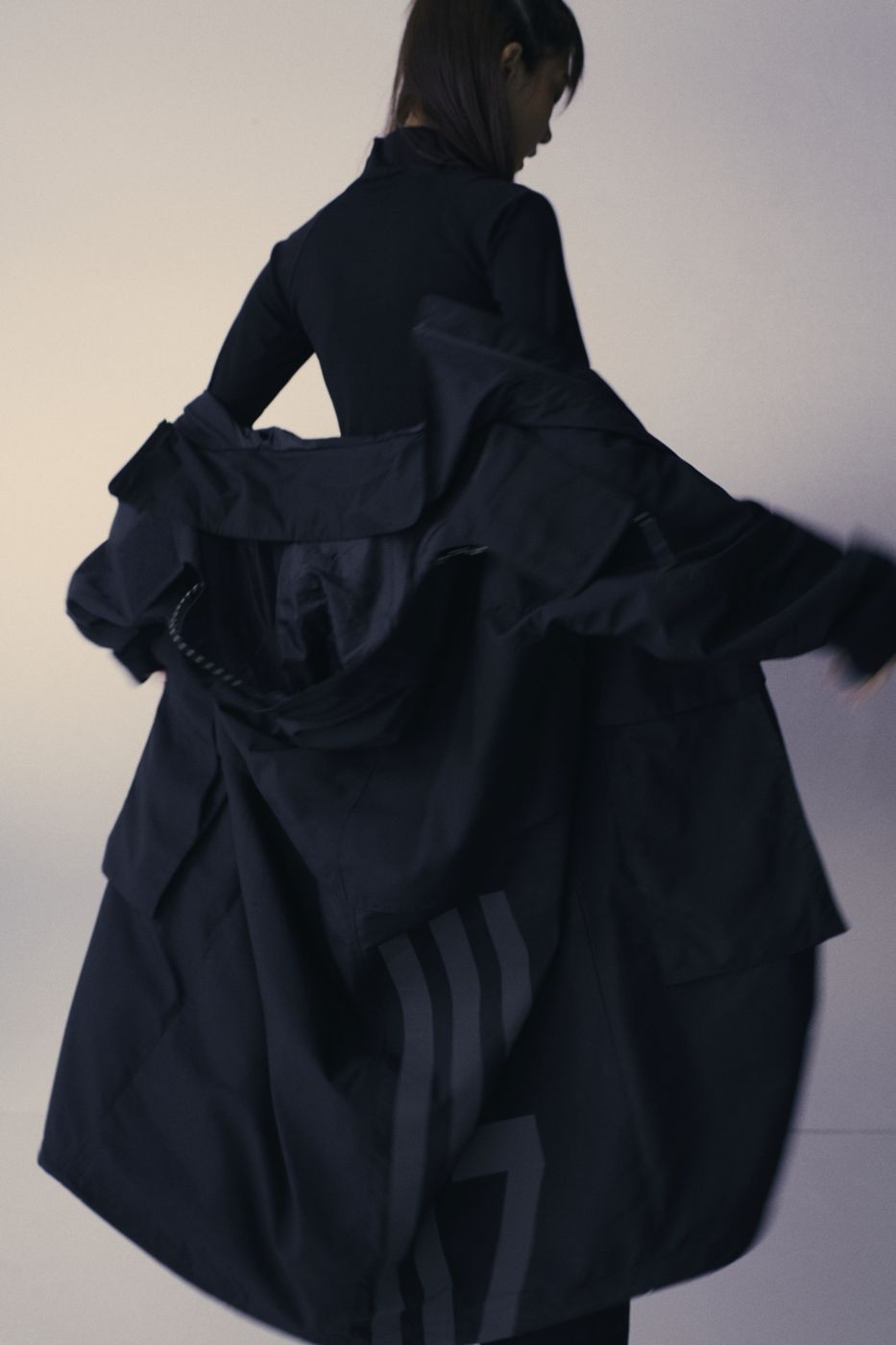 A black coat thrown open in motion